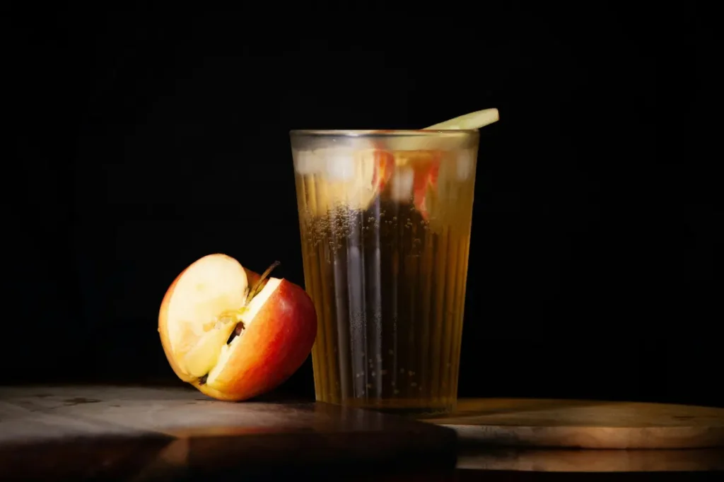Un verre de jus de pomme avec une pomme à côté